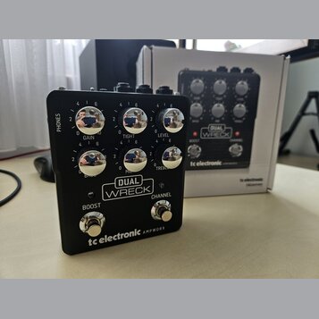 Černý kytarový procesor s nápisem DUAL WRECK a značkou tc electronic AMPWORX. Zařízení má šest otočných ovladačů s popisky GAIN, TIGHT, LEVEL, BASS,…