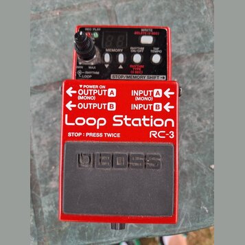 Červený efekt pedál Loop Station RC-3 značky BOSS. Horní panel obsahuje dva digitální displeje, ovládací knoflík a tlačítka s nápisy REC PLAY, WRITE…