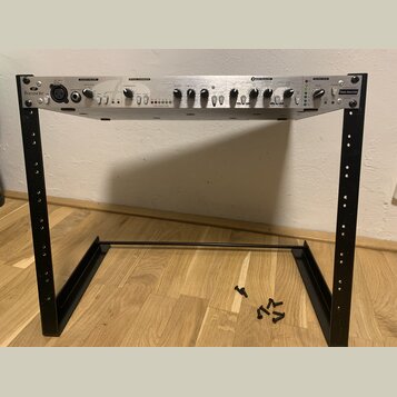 Stříbrný rackový procesor s černými ovládacími prvky umístěný na černém kovovém stojanu. Na zařízení jsou nápisy Focusrite, DISCRETE PREAMP, OPTICAL…