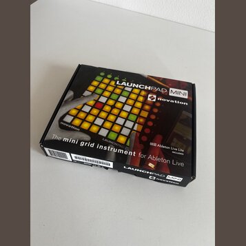 Krabice s MIDI kontrolérem Novation Launchpad Mini. Na povrchu je zobrazen produkt s podsvícenými pady a nápisy LAUNCHPAD MINI, novation, The mini gr…