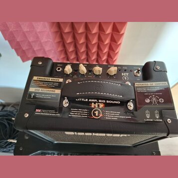 Černý kytarový kombo zesilovač s ovládacím panelem, který obsahuje knoflíky INPUT, GAIN, VOLUME, EQ a REVERB. Na přední straně je nápis HT, logo Blac…