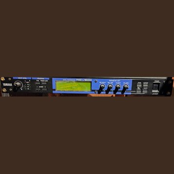 Černý rackový digitální procesor s modrým pruhem na předním panelu. Na zařízení jsou nápisy YAMAHA, DIGITAL REVERBERATOR REV500 a ovládací prvky jako…