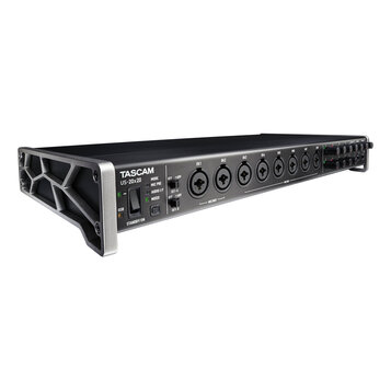 Černý rackový audio rozhraní s kovovým šasi a stříbrnými bočními konzolami. Na předním panelu je nápis TASCAM US-20x20, přepínač STANDBY/ON a osm kom…