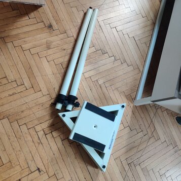 Bílý rozkládací stojan s dvěma teleskopickými trubicemi. Na spodní části je viditelný nápis Millennium a malá bílá nálepka s čárovým kódem. Povrch je…