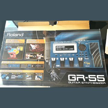 Fotografie znázorňuje krabici od kytarového syntetizátoru s nápisem Roland GR-55 GUITAR SYNTHESIZER. Na obalu je zobrazen modrý přístroj s displejem,…