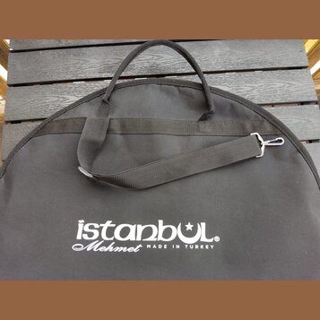 Černý textilní obal na cimbál s rukojetí a ramenním popruhem s kovovým háčkem. Na povrchu je bílý nápis istanbul Mehmet MADE IN TURKEY. Povrch textil…