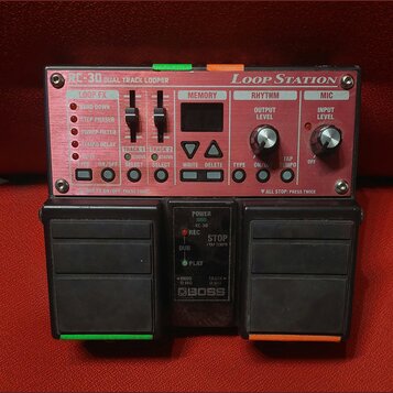 Červený looper s nápisy RC-30 DUAL TRACK LOOPER a LOOP STATION. Zařízení obsahuje několik ovládacích prvků, včetně posuvníků pro LOOP FX a potenciome…