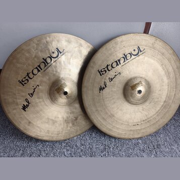 Dvě mosazné činely s viditelným broušením povrchu. Oba mají černý nápis istanbul a menší text Handmade cymbals from Turkey. Pod hlavním logem je na o…