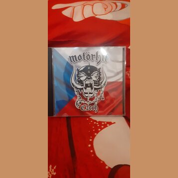 Plastové CD pouzdro s papírovým obalem. Na obalu je zobrazen nápis motörhut, stylizovaná lebka v přilbici s rohy a řetězy na pozadí české vlajky, v d…