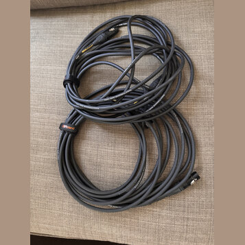 Dvě smotaná audio kabela v šedé barvě. Na kabelech je opakovaně bílý nápis Roland Professional Audio Cable a na jednom z nich je černý textilní pásek…