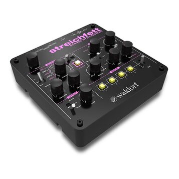 Černý string syntetizér s nápisem streichfett STRING SYNTHESIZER a logem waldorf. Přístroj má mnoho černých ovládacích knoflíků, přepínačů a čtyři žl…