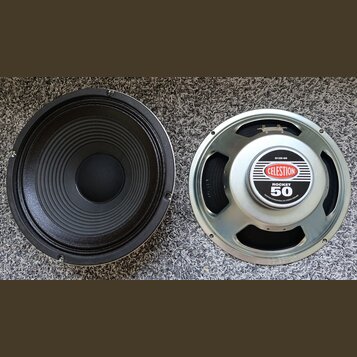 Dvě reproduktorové jednotky v kovovém rámu. Pravý reproduktor má na středovém krytu logo CELESTION a nápisy ROCKET 50 a G12E-50, v dolní části je dro…