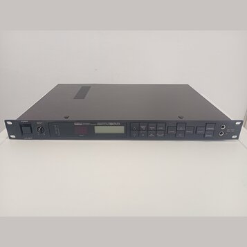 Šedý rackový efektový procesor s kovovým šasi. Na předním panelu je nápis YAMAHA MULTI-EFFECT PROCESSOR SPX900, malý displej a řada ovládacích tlačít…