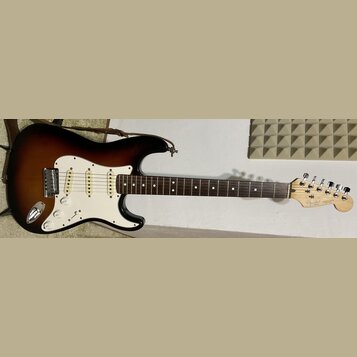 Elektrická kytara typu Stratocaster s barevným přechodem korpusu od černé přes hnědou k žluté. Má bílý pickguard, tři snímače a hnědý hmatník. Na hla…