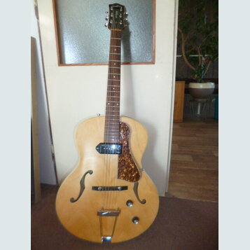 Polodupatá elektrická kytara s přírodním dřevěným povrchem a dvěma f-otvory. Na hlavě je viditelné logo značky Epiphone. Kytara má jeden snímač u krk…