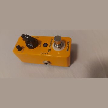 Žlutý efekt pedál s kovovým šasi. Na horní straně je nápis YELLOW COMP a logo MOOER, ovládací knoflík s popiskem VOLUME, menší knoflík COMP a stoupac…