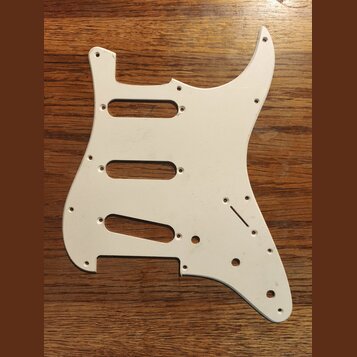 Bílá pickguard pro elektrickou kytaru s třemi výřezy pro snímače. Je vyrobena z plastového materiálu a obsahuje otvory pro šrouby a ovládací prvky. N…