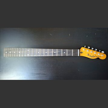 Fotografie zobrazuje krk elektrické kytary s hmatníkem z tmavého dřeva a světle žlutou hlavou. Na hlavě je černé logo Fender, nápis MADE IN USA a mod…