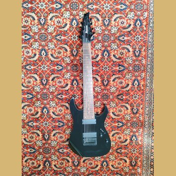 Černá elektrická kytara s tmavým hnedým hmatníkem. Na hlavě je bílý nápis Ibanez. Nástroj má dva humbuckery, jeden ovládací knoflík a přepínač. Povrc…