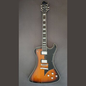 Elektrická kytara s trupem v barevnosti sunburst a černým pickguardem. Na hlavě hmatníku je bílé logo Hagstrom a na zadní straně krku je viditelné sé…