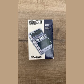 Fotografie znázorňuje papírové krabičku od efekt pedálu. Na krabici je nápis GRUNGE DISTORTION a logo Digitech s mottem The Power to Create. Vizuál z…