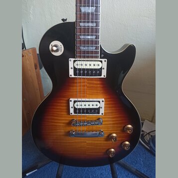 Elektrická kytara s trupem v barevnosti sunburst a černým pickguardem. Na přepínači je viditelný nápis RHYTHM TREBLE a na spodním snímači je nápis R.…