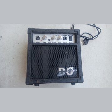 Černý kytarový kombozesilovač s texturovaným povrchem a kovovou mřížkou reproduktoru. Na horním ovládacím panelu je nápis GUITAR AMPLIFIER GL-10 a po…