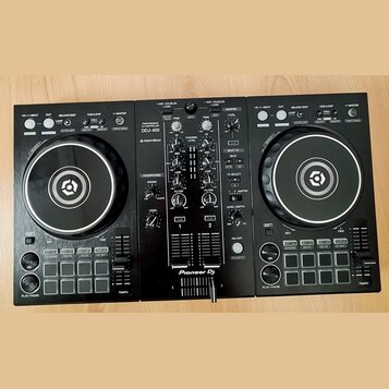 Černý DJ kontrolér Pioneer DJ DDJ-400. Na přístroji jsou viditelné nápisy PERFORMANCE DJ CONTROLLER, DDJ-400 a logo rekordbox. Zařízení obsahuje dva…