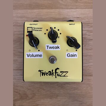 Žlutý kytarový efekt s nápisem TweakFuzz v dolní části. Na horní straně je logo Seymour Duncan a popisy OUTPUT a INPUT. Zařízení má tři černé ovládac…