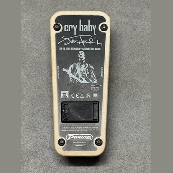 Zadní strana efekt pedálu s krémovým rámem a černým kovovým krytem. Na krytu je bílý nápis cry baby, podpis Jimi Hendrix a text JH-1B JIMI HENDRIX SI…