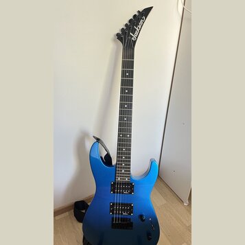 Modře lakovaná elektrická kytara s černým hmatníkem a černými hardwarem. Na hlavě je bílý nápis Jackson. Nástroj má dva humbuckery, jeden ovládací kn…