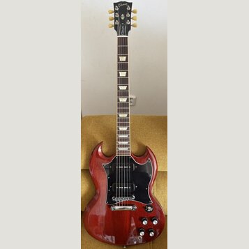 Elektrická kytara s červeným lakem a černým pickguardem. Na hlavě hmatníku je bílý nápis Gibson a na spodní části nápis Standard. Kytara má dva humbu…