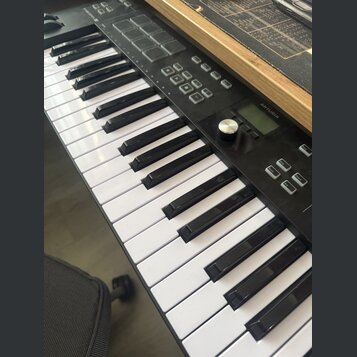 Černý MIDI kontrolér s klávesnicí. Na horním panelu je vidět nápis ARTURIA, sada padů a ovládací tlačítka s popisky Octave, Octave, Chord a Arp. Povr…