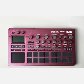 Bordeaux červený sampler KORG electribe sampler MUSIC PRODUCTION STATION. Zařízení obsahuje displej, několik otočných potenciometrů a mřížku šestiдес…