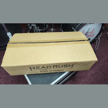 Hnědý kartonový obal s nápisy. Na boku je černý text „HEAD RUSH“, pod ním označení „C/NO. 119“ a dále „MADE IN TAIWAN“. Krabice vykazuje mírné pomačk…