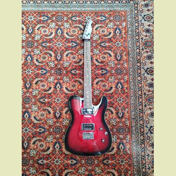 Elektrická kytara s červeným gradientem (sunburst) a viditelnou strukturou dřeva. Nástroj má dva humbuckery, jeden tónový potenciometr a jeden přepín…