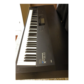 Černý digitální klavír s klasickou klávesnicí. Na pravé straně korpusu je nápis KORG a vedle něj označení 01/W ProX MUSIC WORKSTATION. V horní části…