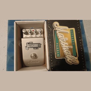 Stříbrný efekt pedál s nápisem THE JACKHAMMER JH-1 a logem Marshall v dolní části. Pedál má čtyři ovládací knoflíky s popisky MODE, VOLUME, BASS a CO…