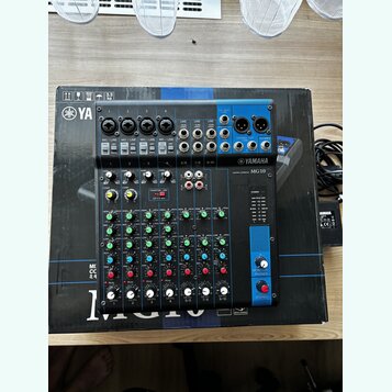 Modrá míchací konzole Yamaha MG10 v originální krabici. Na předním panelu jsou viditelná loga YAMAHA a označení MIXING CONSOLE MG10. Zařízení obsahuj…