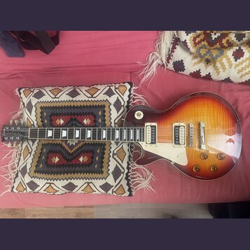 Elektrická kytara s trupem ve tvaru singlecut a barevným přechodem od žluté k tmavě hnědé (sunburst). Na hlavě je viditelné logo "Epiphone". Nástroj…