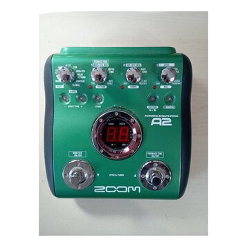 Zelený efektový pedál s nápisem ACOUSTIC EFFECTS PEDAL A2 a logem ZOOM v dolní části. Zařízení obsahuje několik otočných potenciometrů, červené kontr…
