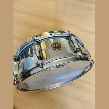 Stříbrný kovový malý buben s chromovaným povrchem. Na korpusu je umístěno kulaté logo s nápisem Gretsch, ORIGINAL SINCE 1881. Na horním obruči je vid…