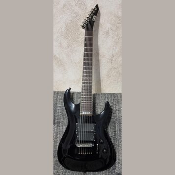 Černá elektrická kytara s tmavým hnedým hmatníkem. Na hlavě je bílý nápis LTD. Nástroj má dva humbuckery, jeden ovládací knoflík a přepínač. Povrch t…