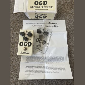 Bílý efekt pedál s nápisy OCD a Fulltone. Pedál má tři černé ovládací knoflíky s popisky Volume, Drive a Tone. Součástí je originální krabice s nápis…