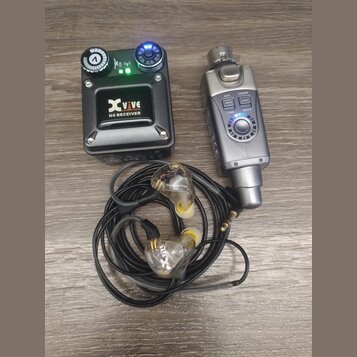Černý přijímač s nápisy Xvive a U4 RECEIVER, vybavený dvěma ovladačovacími knoflíky a kontrolkami. Vedle něj je stříbrný bezdrátový vysílač s tlačítk…
