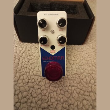 Bílý efekt pedál s červeným spínacím tlačítkem. Na horní části jsou čtyři černé ovládací knoflíky s popisky TIME, BLEND, MODULATION a FEEDBACK. Upros…