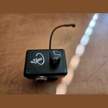 Černý kovový box s jedním ovládacím knoflíkem a tenkou anténou. Na přední straně je bílé logo s nápisem Myers. Box je upevněn čtyřmi křížovými šrouby…