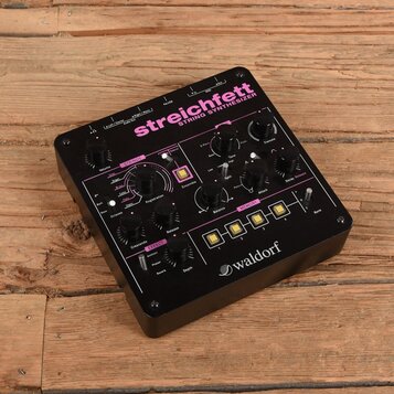 Černý string syntetizér s růžovými detaily a nápisy. Na horní části je velký nápis streichfett STRING SYNTHESIZER a v pravém dolním rohu logo waldorf…
