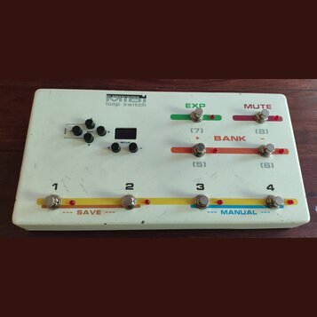 Bílý MIDI loop switch od značky m.electronics. Zařízení má osm stisknutelných tlačítek, malý displej a čtyři ovládací knoflíky. Na povrchu jsou nápis…