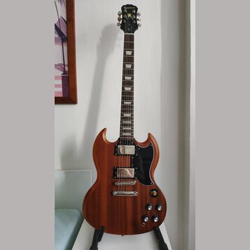 Elektrická kytara s hnědým dřevěným povrchem a černým pickguardem. Na hlavě hmatníku je bílý nápis Epiphone. Nástroj má dva humbuckery, Tune-o-matic…